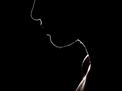 Silhouette of a man stretching against a dark background.